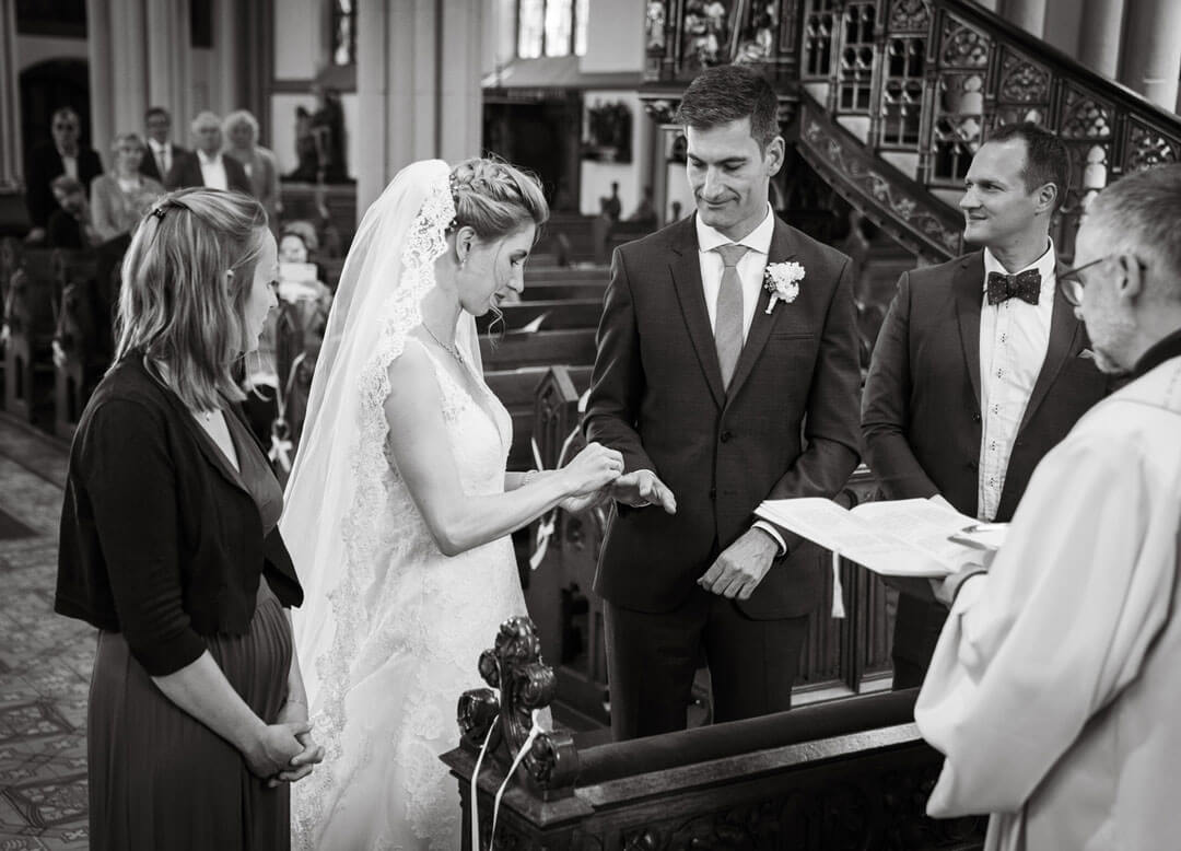 Hochzeitsfoto von Ehepaar, Bräutigam steckt Braut den Ring an